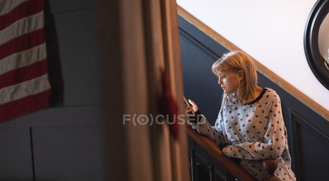 Mulher bonita usando telefone celular nas escadas em casa — Fotografia de Stock