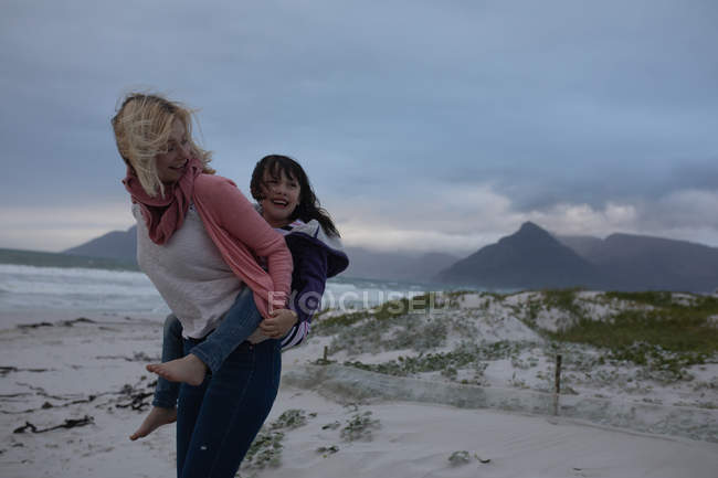 Mãe e filha se divertindo na praia durante o inverno — Fotografia de Stock