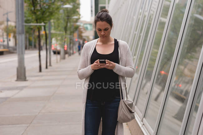 Belle femme utilisant le téléphone portable dans la ville — Photo de stock