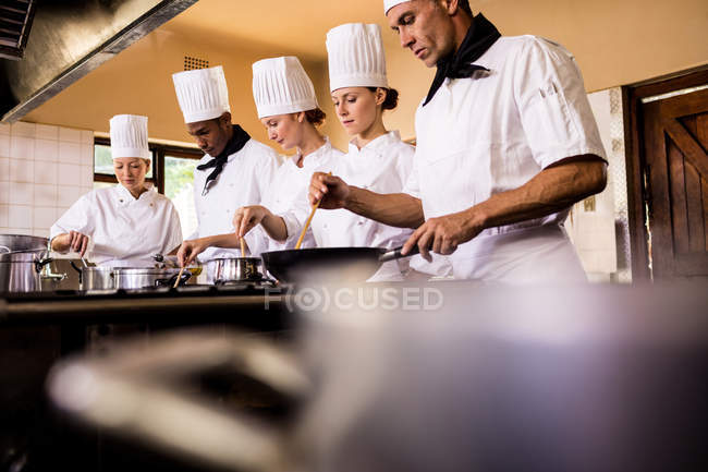 Grupo de chef preparando comida na cozinha — Fotografia de Stock
