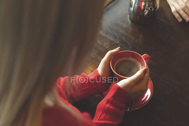 Donna che tiene una tazza di caffè sul tavolo nel caffè — Foto stock