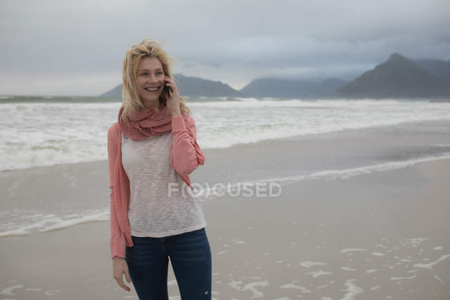 Mujer feliz hablando por teléfono móvil en la playa - foto de stock