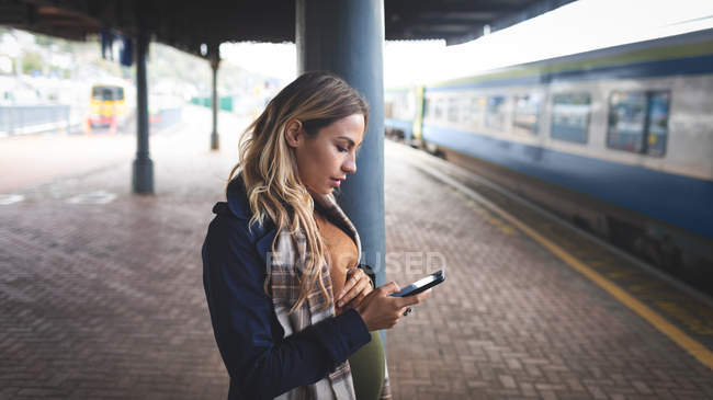 Side view of pregnant woman using mobile phone at railway station — Stock Photo