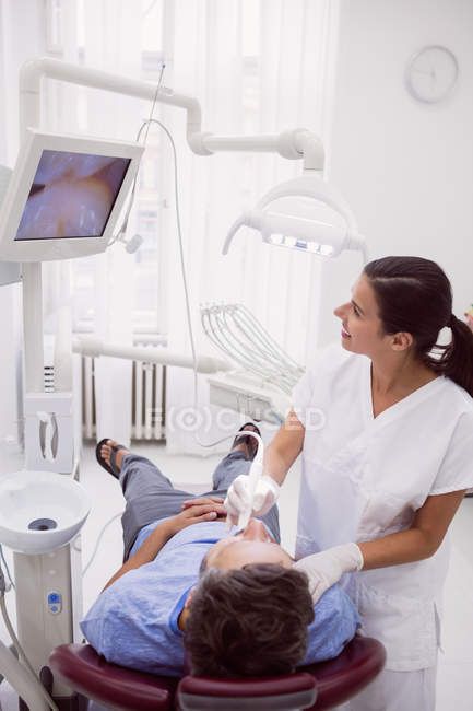 Dentista feminina examinando paciente em clínica odontológica — Fotografia de Stock