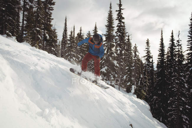 Homme snowboard en montagne contre les arbres — Photo de stock