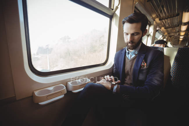 Бізнесмен перевіряє час на смарт-годиннику під час подорожі в поїзді — стокове фото