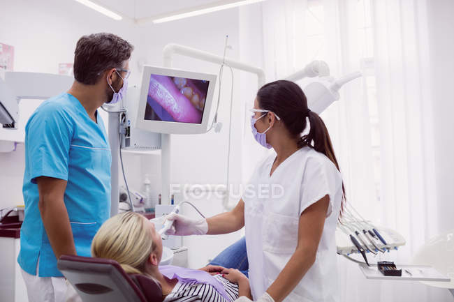 Dentistes masculins et féminins examinant le patient en clinique dentaire — Photo de stock