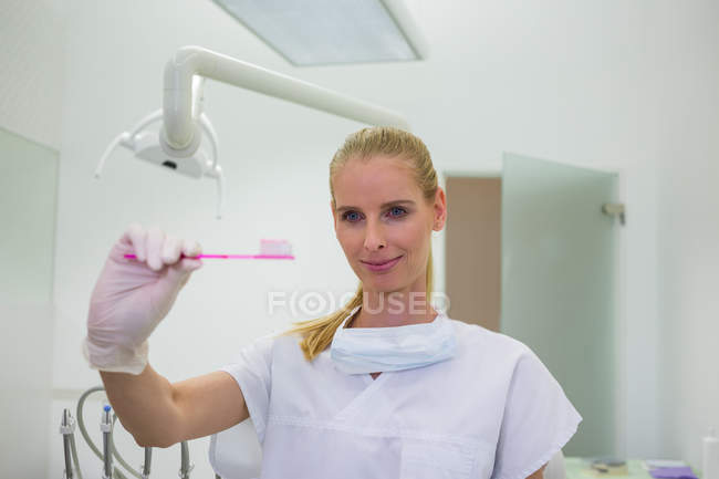 Female dentist holding pink toothbrush at clinic — Stock Photo