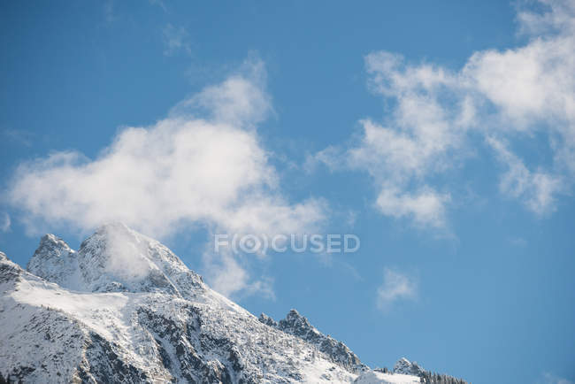 Ruhiger Blick auf wunderschöne schneebedeckte Gebirgsketten vor blauem Himmel und Wolken — Stockfoto