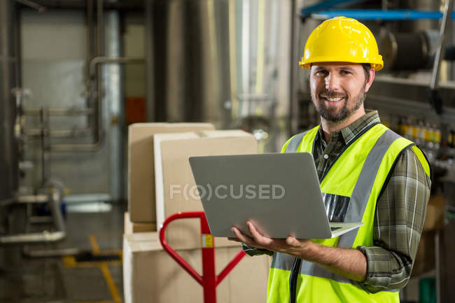 Портрет усміхненого працівника-чоловіка, який використовує ноутбук на складі розповсюдження — стокове фото