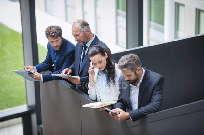 Empresários usando celular e tablet digital no escritório — Fotografia de Stock