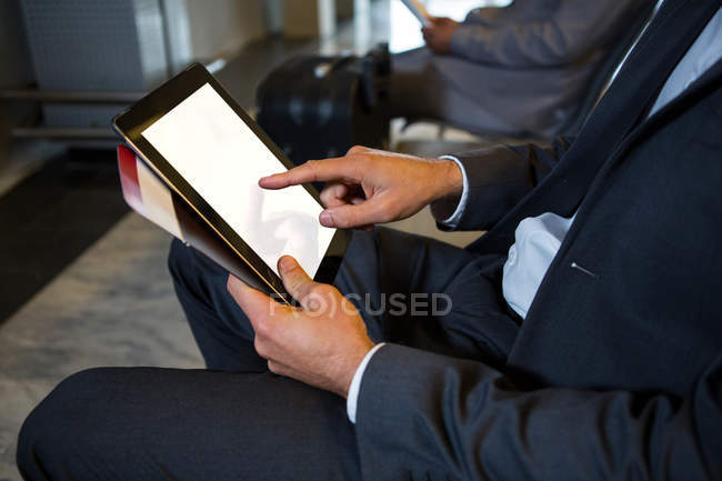 Meio-seção de homem de negócios usando tablet digital enquanto sentado no terminal do aeroporto — Fotografia de Stock