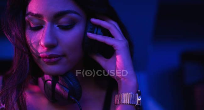 Beautiful female dj listening to music in headphones at bar — Stock Photo