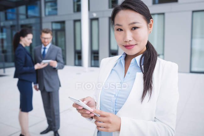 Портрет предпринимательницы с помощью мобильного телефона в офисе — стоковое фото