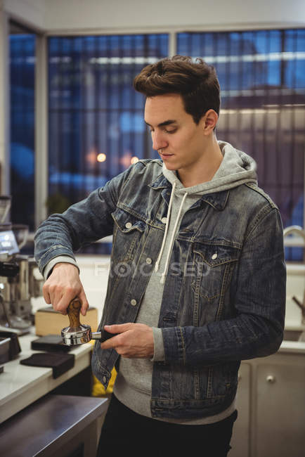 Uomo che preme caffè con manomissione in portafilter in caffetteria — Foto stock