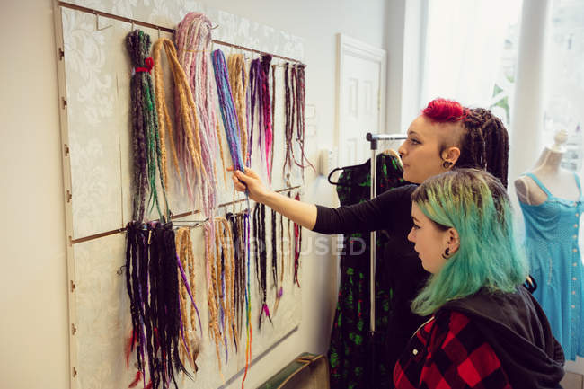 Female shop owner showing dreadlocks to a customer in shop — Stock Photo