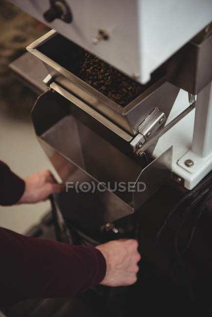 Man holding plastic bag in front of weighing machine in coffee shop — Stock Photo