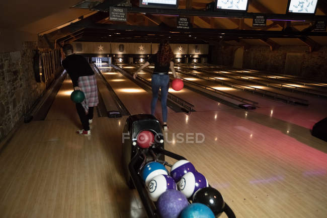 Rear view of two young people bowling at bowling alley — Stock Photo