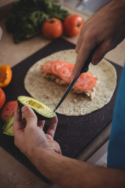 Close-up of male hands cutting avocado in kitchen at home — Stock Photo