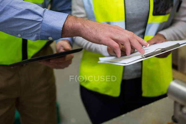 Close-up of technicians discussion over clipboard — Stock Photo