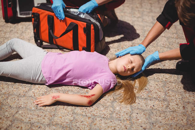 Les ambulanciers examinent une fille blessée dans la rue — Photo de stock