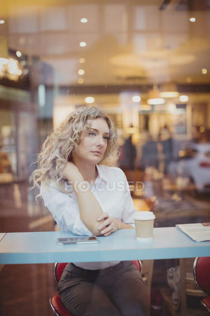 Nachdenkliche Frau sitzt in Cafeteria am Tresen — Stockfoto