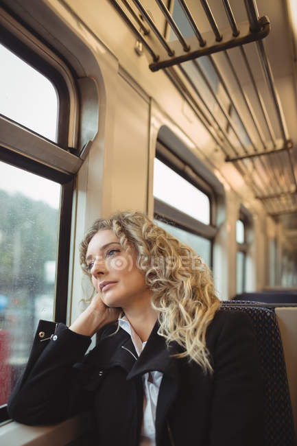 Empresária atenciosa sentada no trem e olhando pela janela — Fotografia de Stock