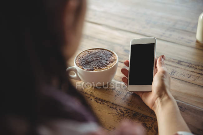 Woman holding mobile phone in cafe — Stock Photo
