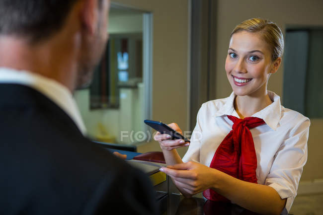 Female scanning the boarding pass with mobile phone at airport terminal — Stock Photo