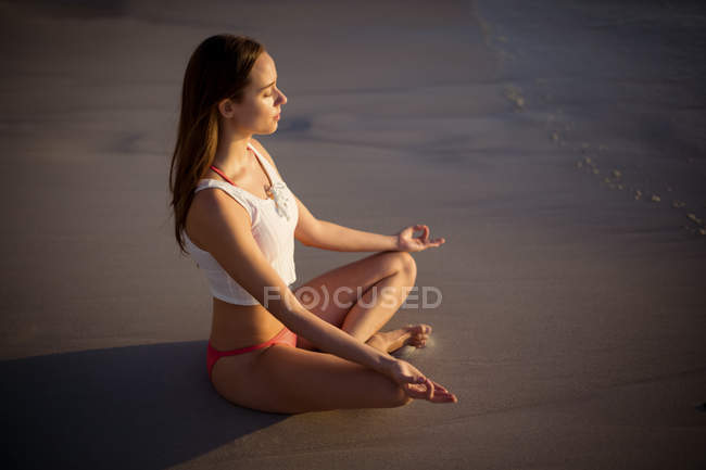 Красивая женщина, занимающаяся йогой на пляже в солнечный день — стоковое фото