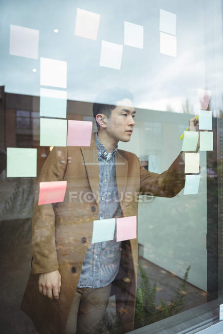 Бизнес-руководитель пишет на липких бумажках в офисе — стоковое фото
