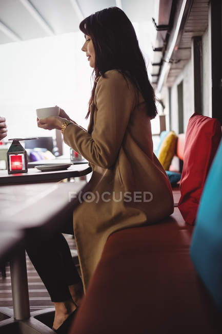 Donna che tiene una tazza di caffè nel ristorante — Foto stock