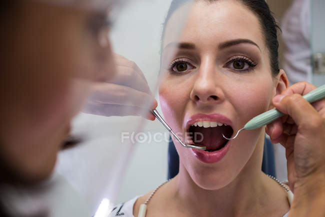 Zahnarzt untersucht Patientin in Zahnklinik mit Werkzeug — Stockfoto