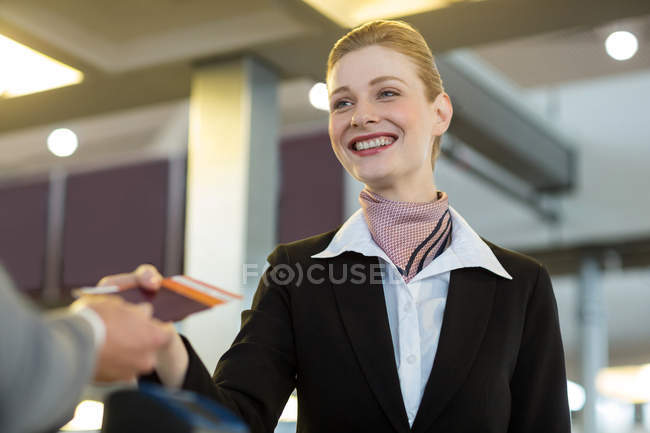Airline check-in attendant handing passport to commuter at counter in airport terminal — Stock Photo