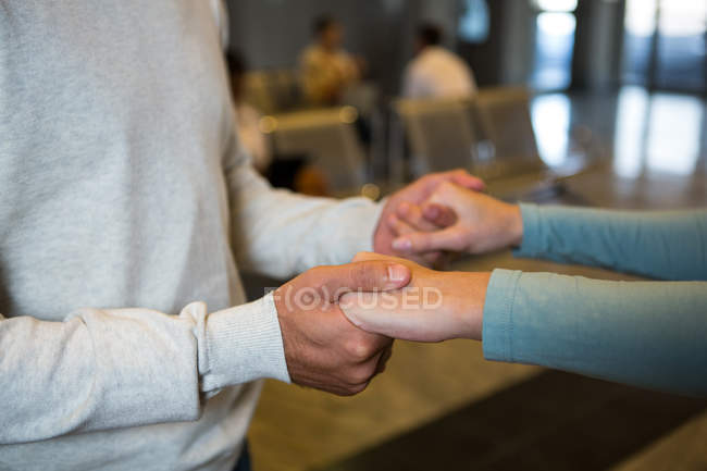 Mid-section of couple holding hands in waiting area at airport terminal — Stock Photo