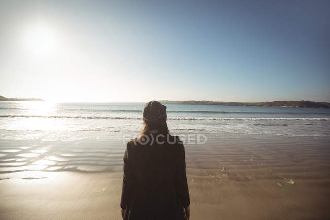 Rear view of woman standing on beach during day — Stock Photo