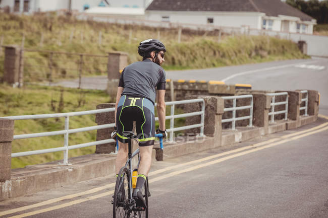 Visão traseira do atleta andar de bicicleta na estrada rural — Fotografia de Stock