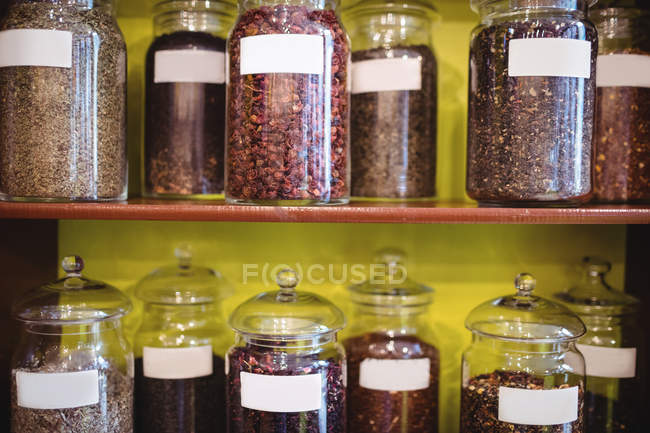 Various spices jars arranged on shelves in shop — Stock Photo