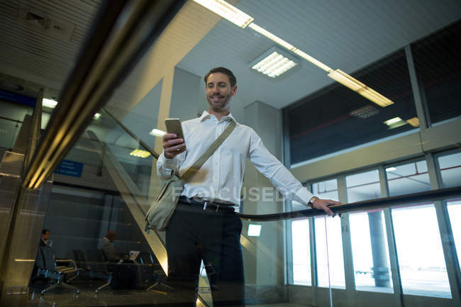Handsome man using mobile phone on escalator in airport — Stock Photo