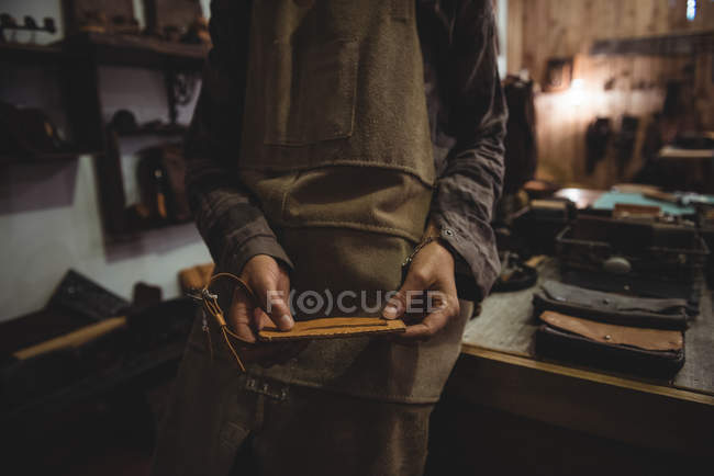 Mid-section of craftswoman holding wallet in workshop — Stock Photo