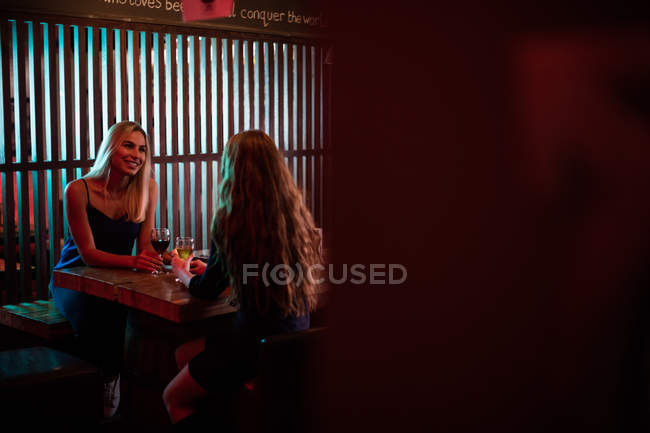 Дві жінки взаємодіють, маючи келих вина в барі — стокове фото
