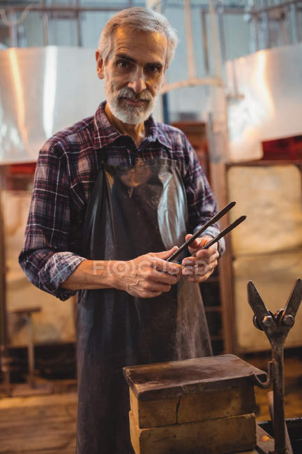 Portrait of glassblower holding tongs at glassblowing factory — Stock Photo