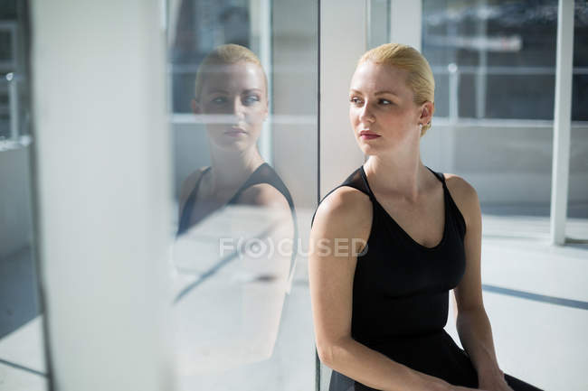 Bailarina sentada contra ventana de cristal en el estudio - foto de stock