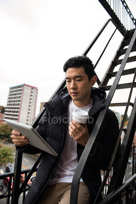 Людина використовує цифровий планшет, маючи каву на балконі — стокове фото