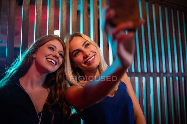 Happy friends taking selfie from mobile phone in bar — Stock Photo