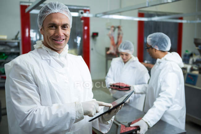 Retrato de técnicos usando tablet digital na fábrica de carne — Fotografia de Stock