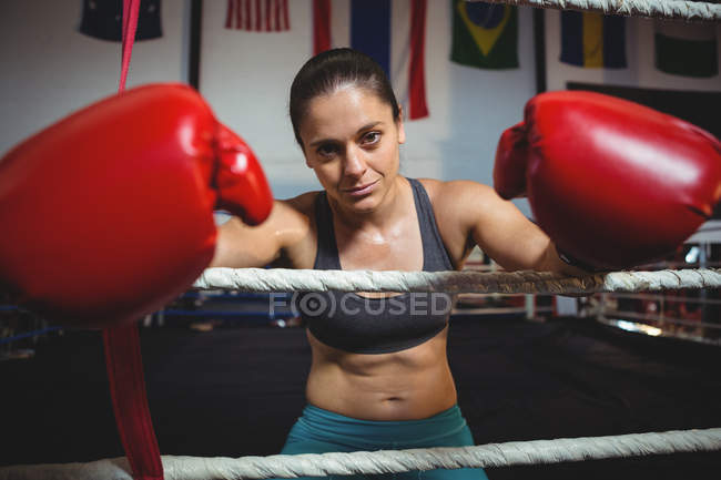 Female boxer with boxing gloves in boxing ring at fitness studio — Stock Photo