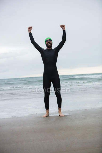 Retrato de atleta gritando en la playa con las manos levantadas - foto de stock