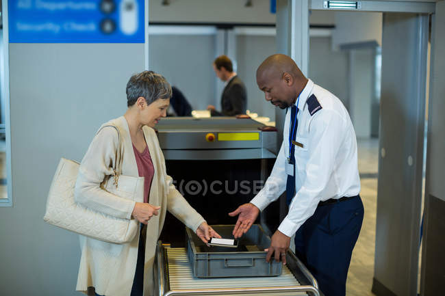 Agent de sécurité de l'aéroport vérifiant le téléphone mobile de navette dans le terminal de l'aéroport — Photo de stock