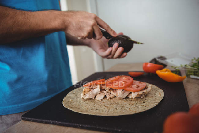 Primo piano di mani maschili che tagliano l'avocado in cucina a casa — Foto stock
